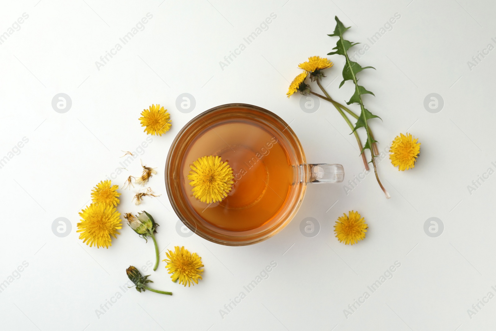 Photo of Delicious fresh tea and dandelion flowers on white table, flat lay