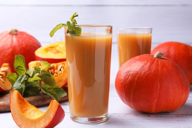 Photo of Tasty pumpkin juice and pumpkins on white wooden table