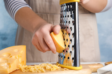 Photo of Woman grating fresh cheese at table, closeup