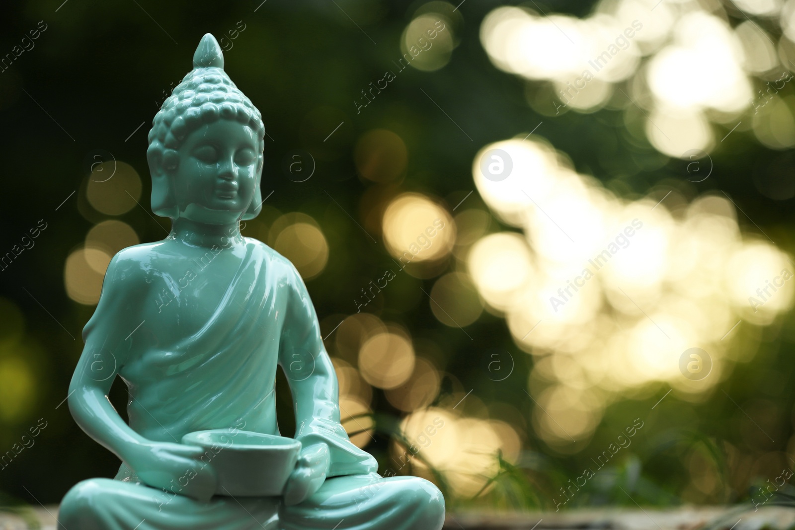 Photo of Decorative Buddha statue on blurred background outdoors. Space for text