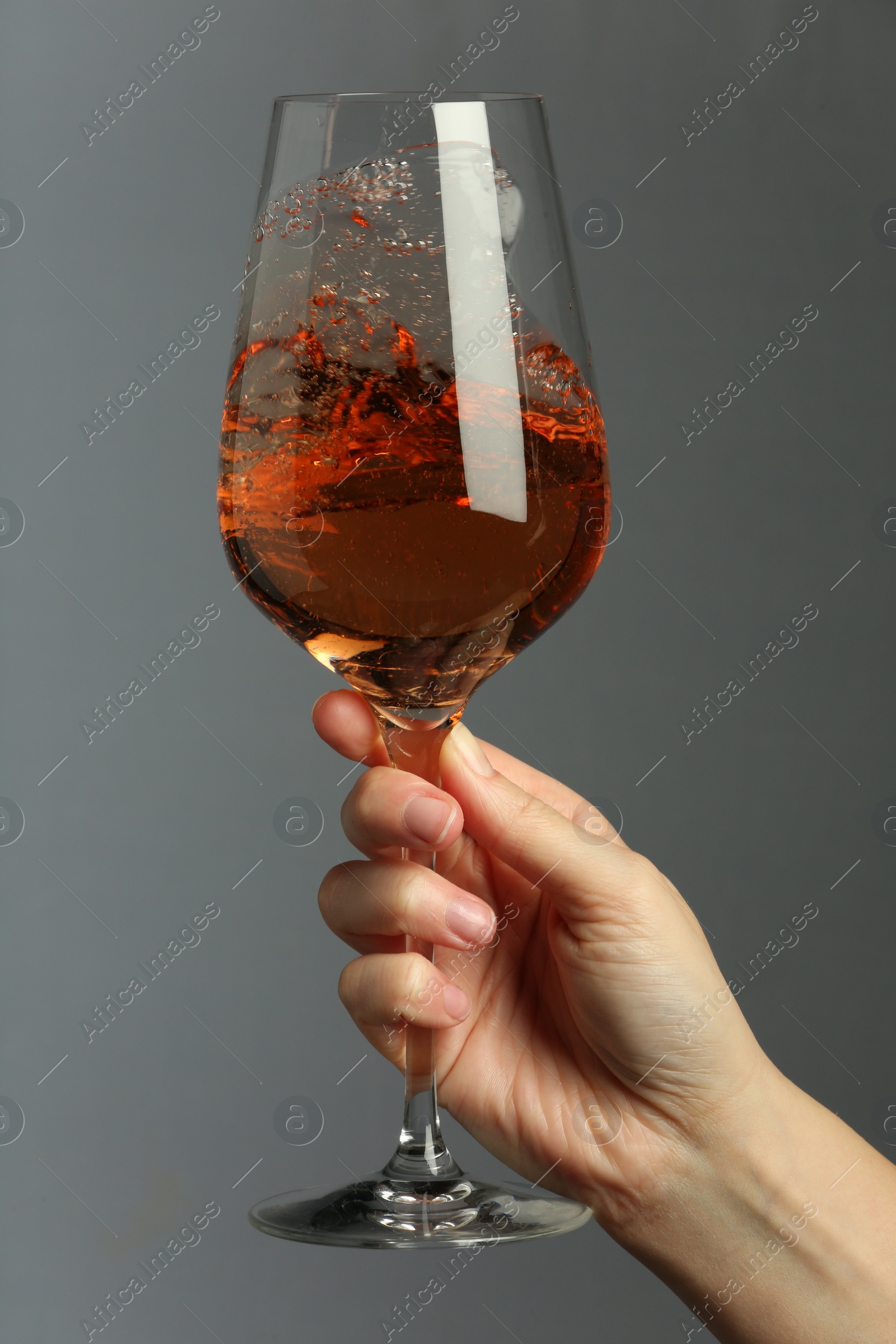 Photo of Woman with glass of aromatic wine on grey background, closeup