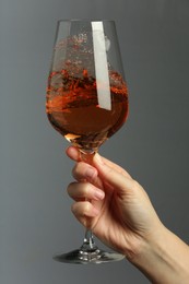 Woman with glass of aromatic wine on grey background, closeup