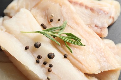 Pieces of raw cod fish, rosemary and peppercorns on table, closeup