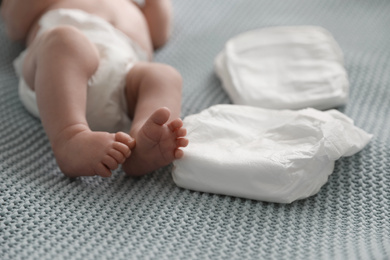 Cute little baby in diaper lying on bed, closeup