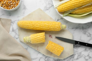 Tasty fresh corn cobs on white marble table, flat lay