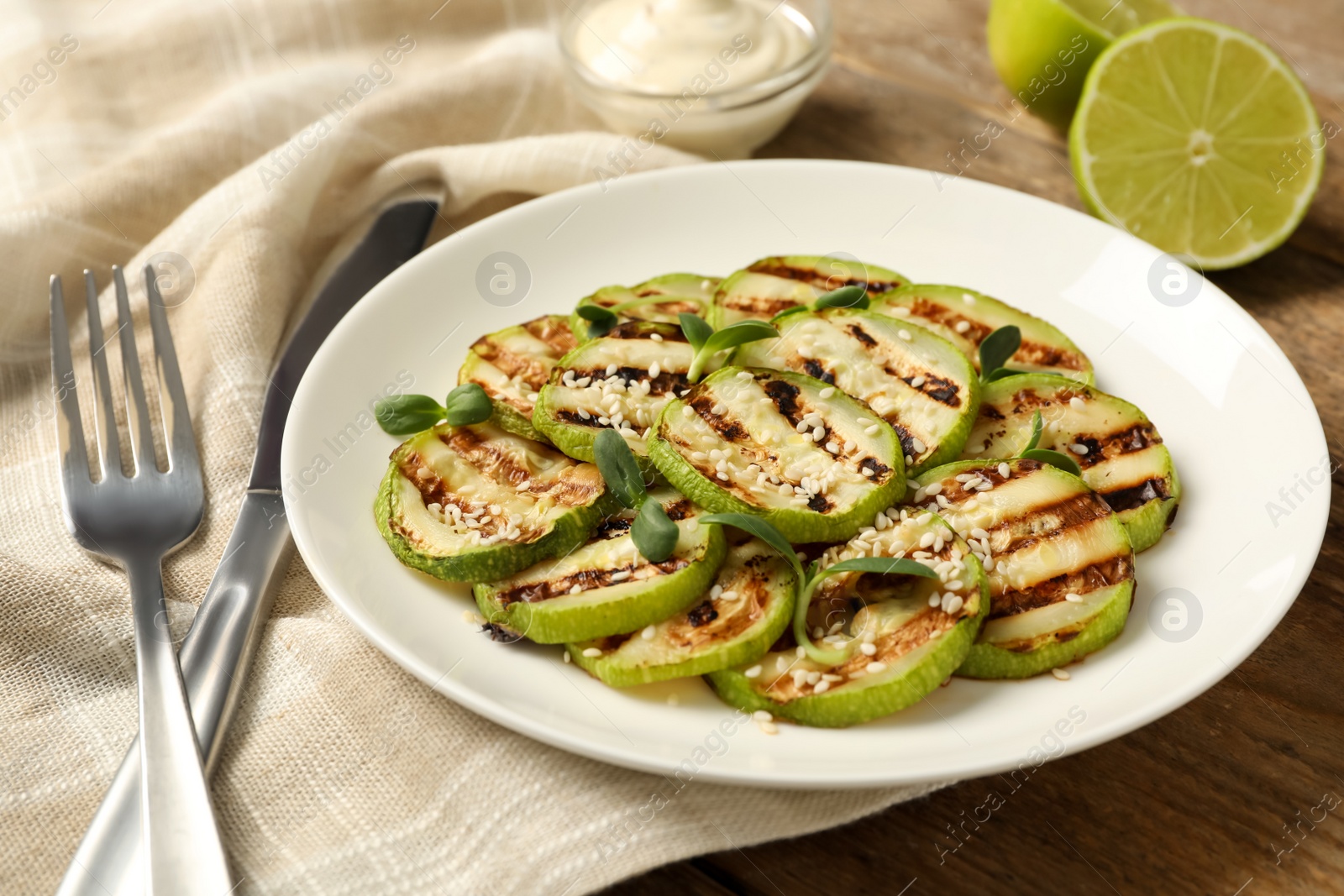 Photo of Delicious grilled zucchini slices served on wooden table, closeup