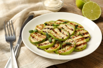 Photo of Delicious grilled zucchini slices served on wooden table, closeup