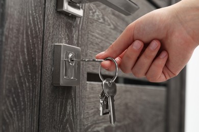 Woman unlocking door with key, closeup view