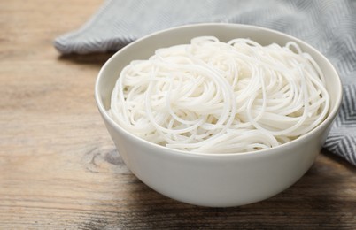Photo of Bowl with cooked rice noodles on wooden table, closeup