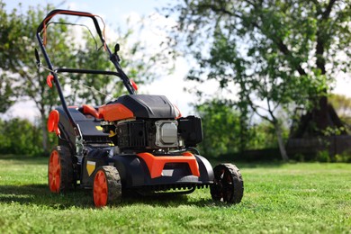 Photo of Modern lawn mower on green grass in garden