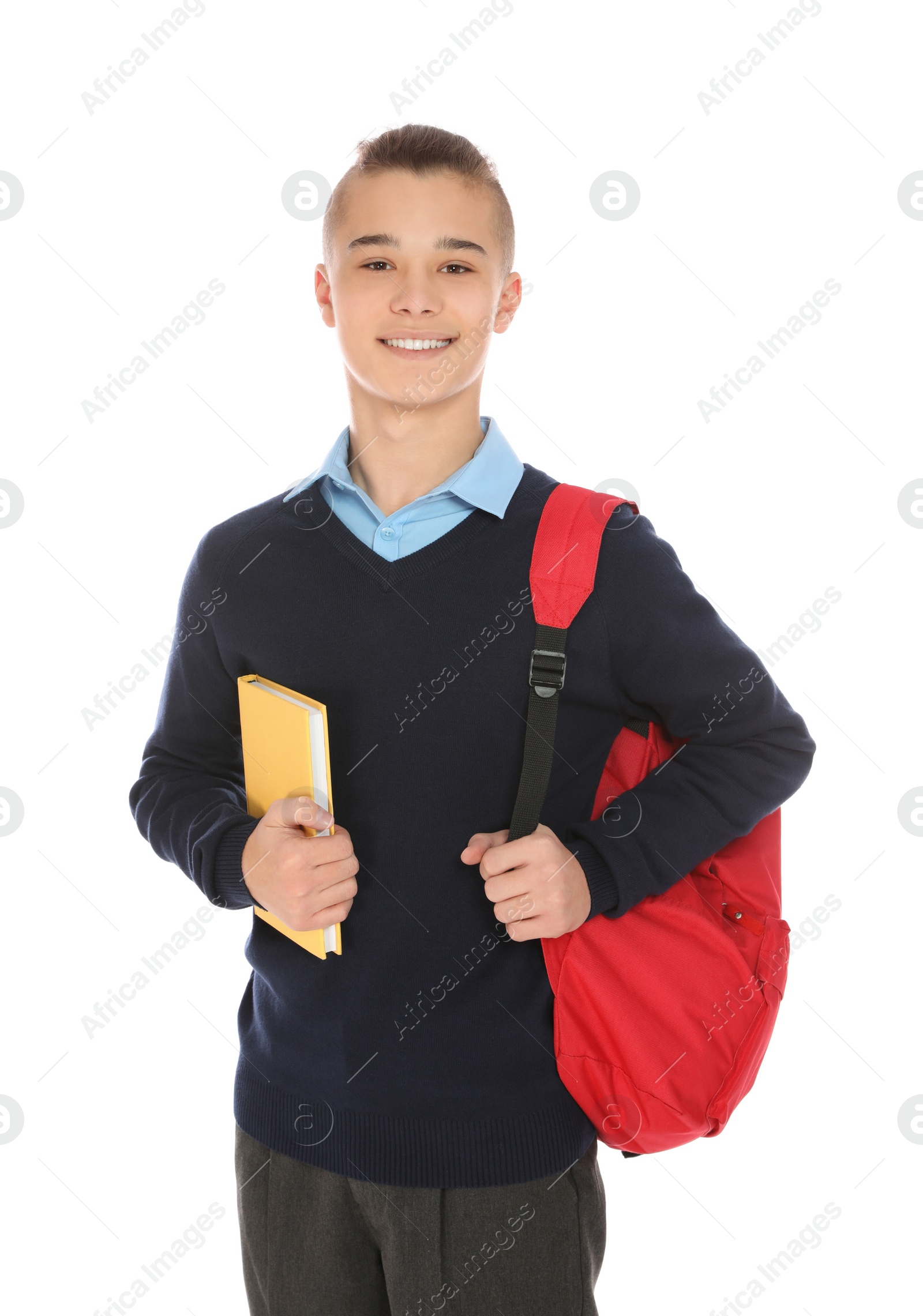 Photo of Portrait of teenage boy in school uniform with backpack and book on white background