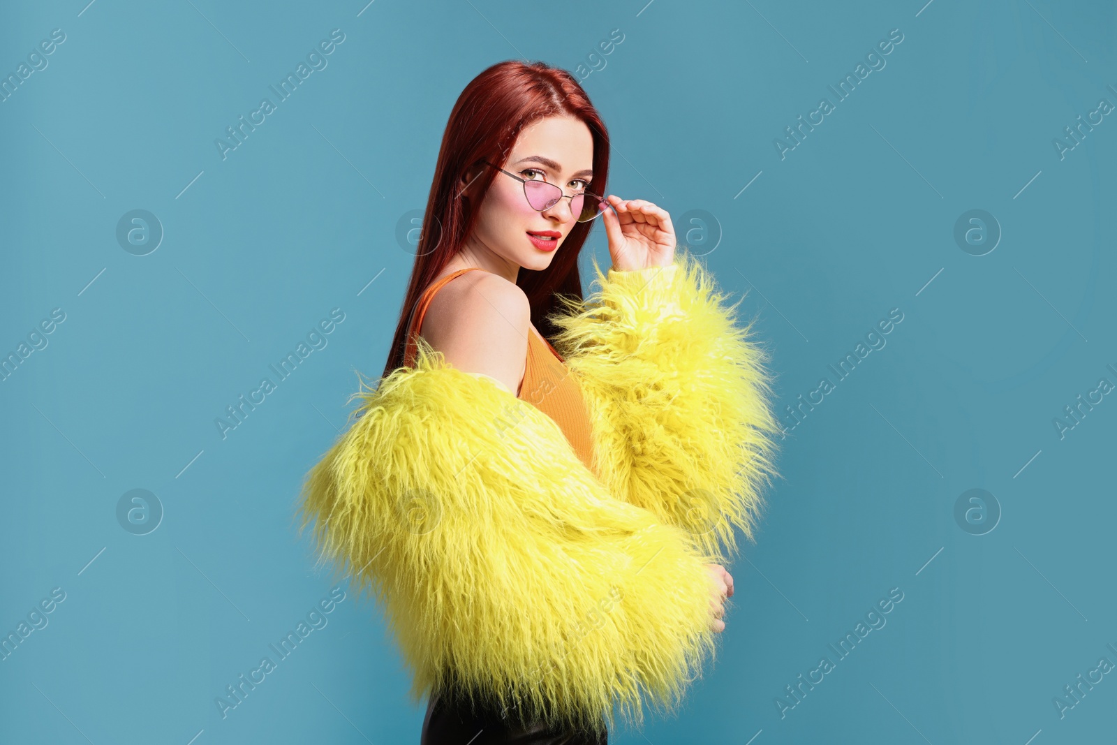 Photo of Stylish woman with red dyed hair on light blue background