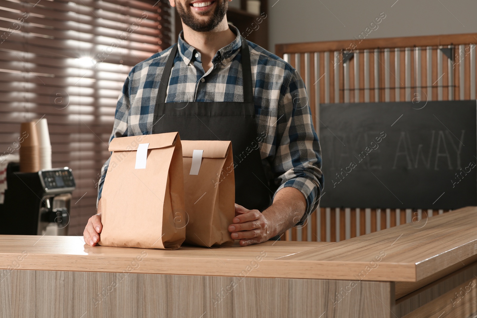 Photo of Worker with paper bags at counter in cafe, closeup