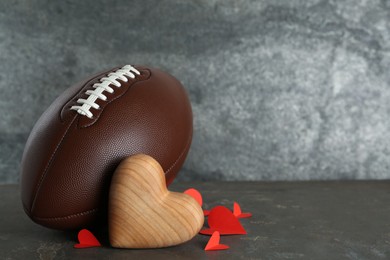 American football ball and hearts on grey table. Space for text