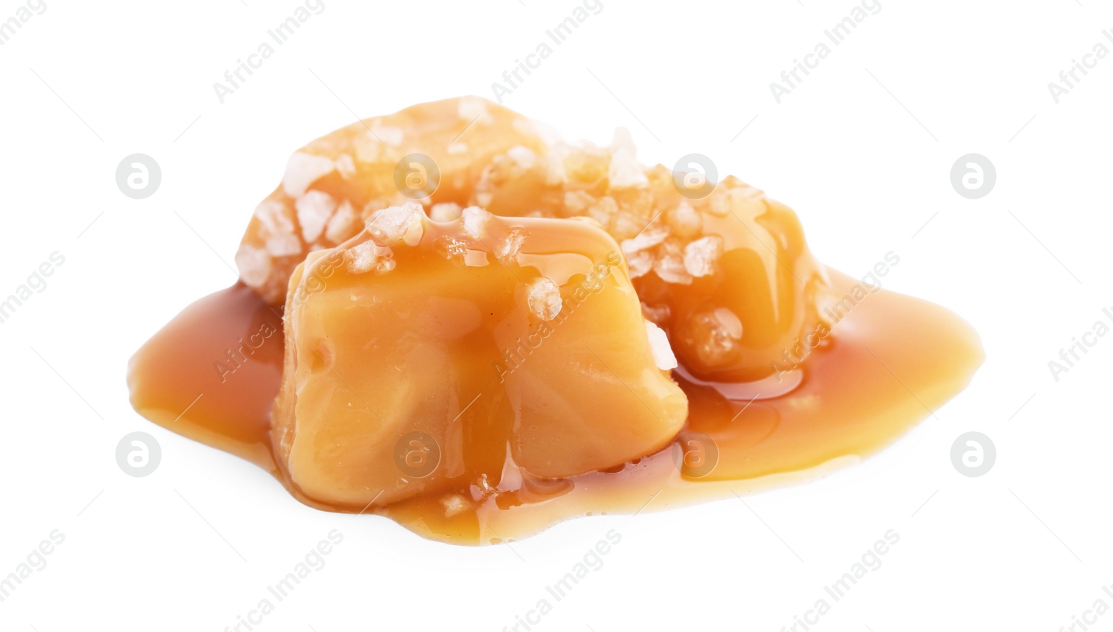 Photo of Yummy caramel candies and sea salt isolated on white