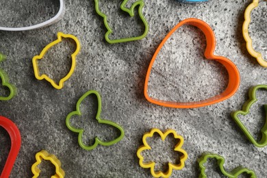 Photo of Set of different cookie cutters on grey table, flat lay. Cooking utensils