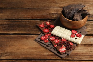 Photo of Different chocolate bars with freeze dried fruits on wooden table. Space for text