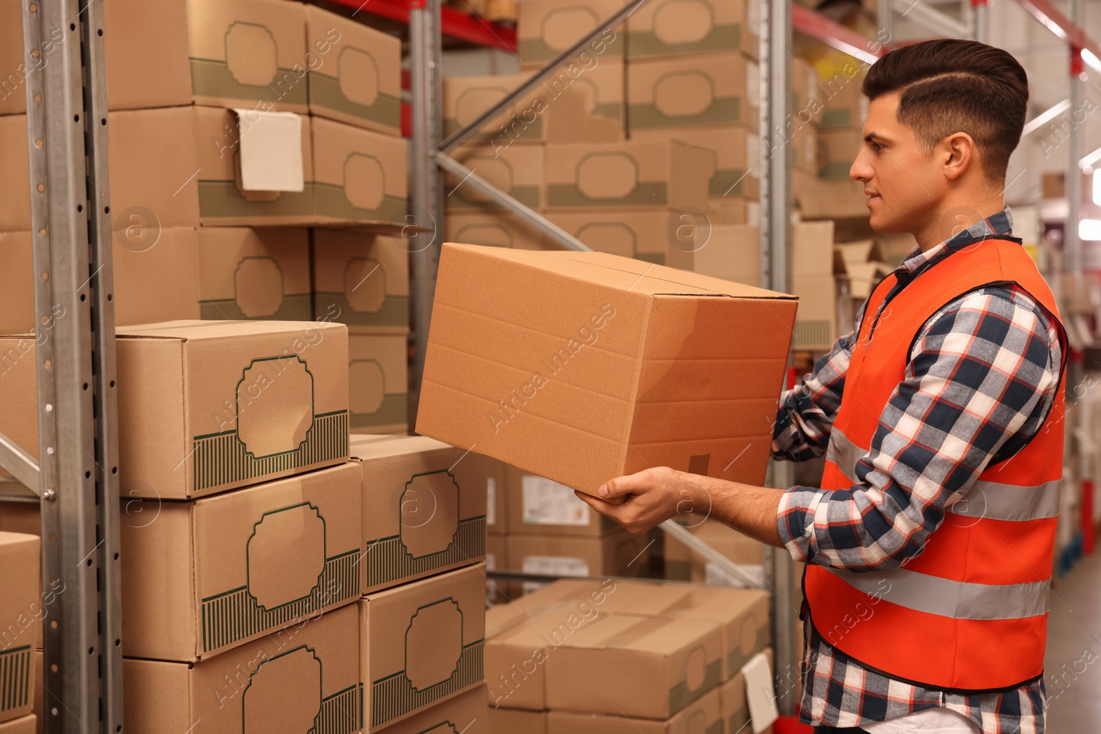 Photo of Worker stacking cardboard boxes in warehouse. Wholesaling