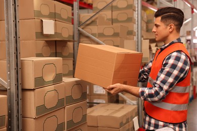 Worker stacking cardboard boxes in warehouse. Wholesaling
