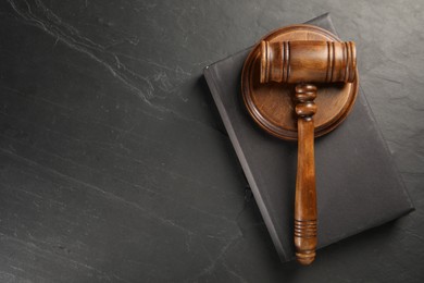 Photo of Wooden gavel, sound block and book on dark textured table, top view. Space for text