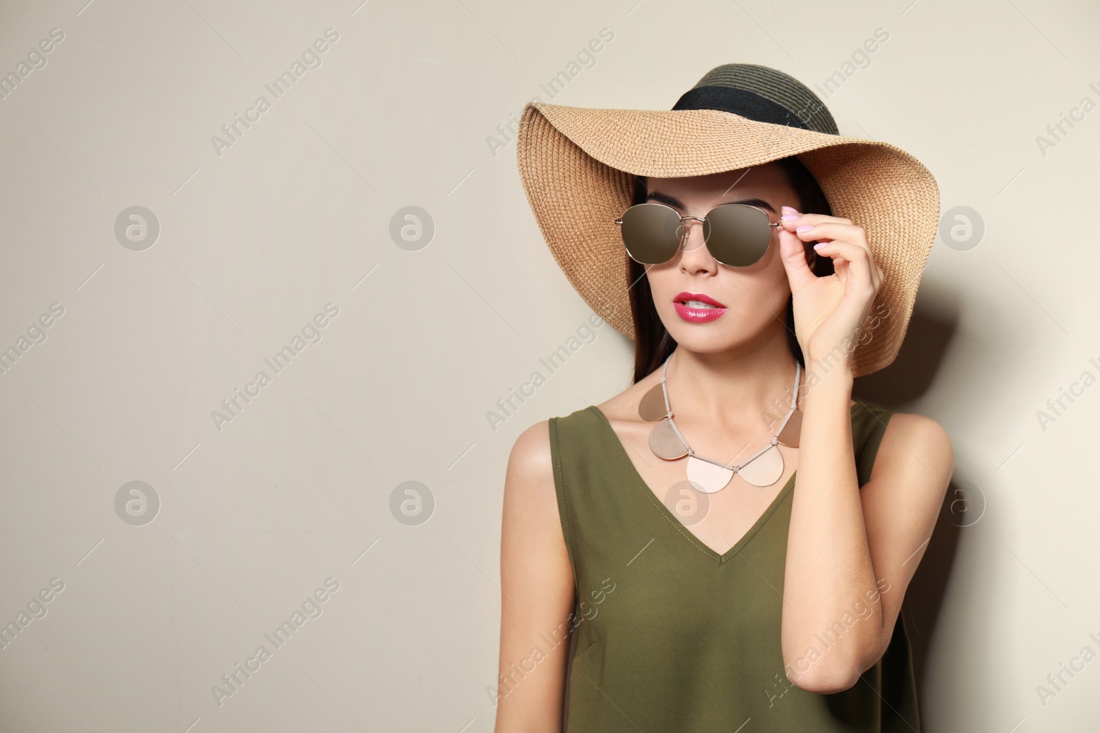 Photo of Beautiful woman in stylish sunglasses and hat on beige background. Space for text