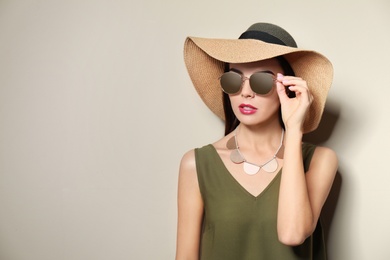 Photo of Beautiful woman in stylish sunglasses and hat on beige background. Space for text