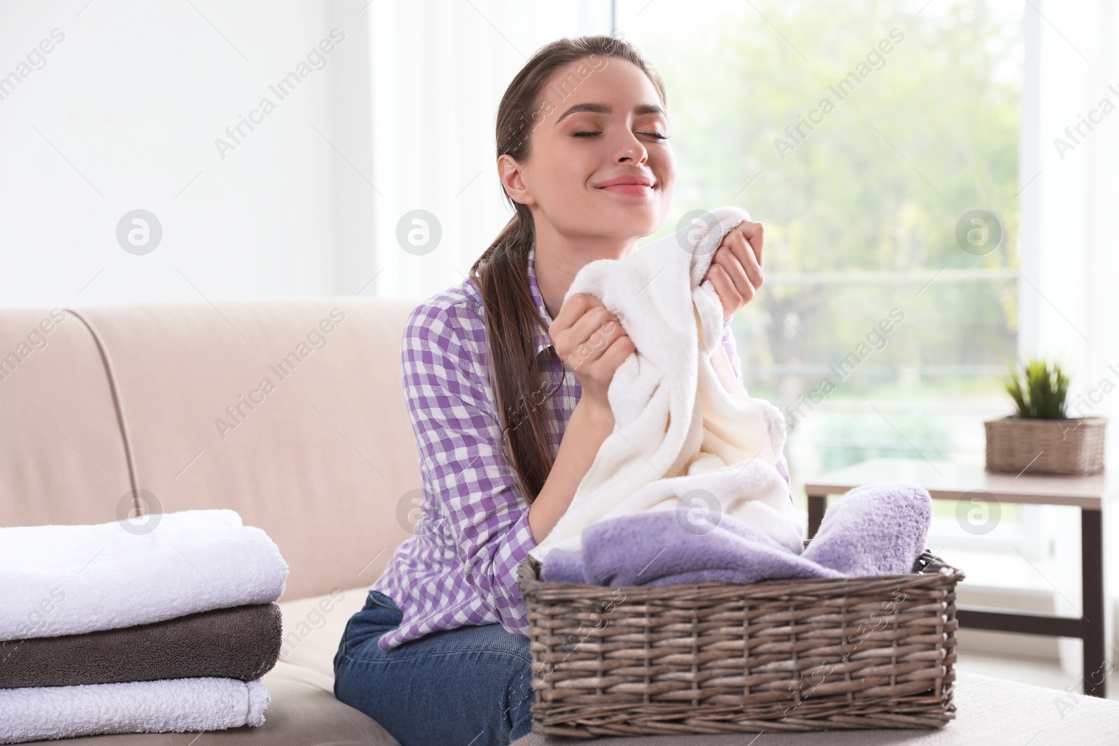 Photo of Happy woman with basket of laundry in living room