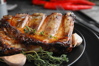 Photo of Tasty grilled ribs with thyme on plate, closeup