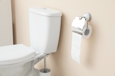 Photo of Holder with toilet paper roll on wall in bathroom