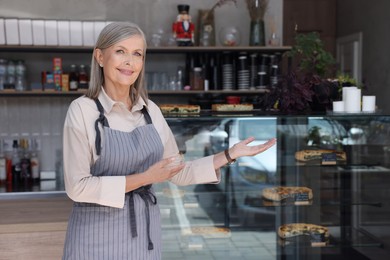 Happy business owner inviting to come into her cafe, space for text