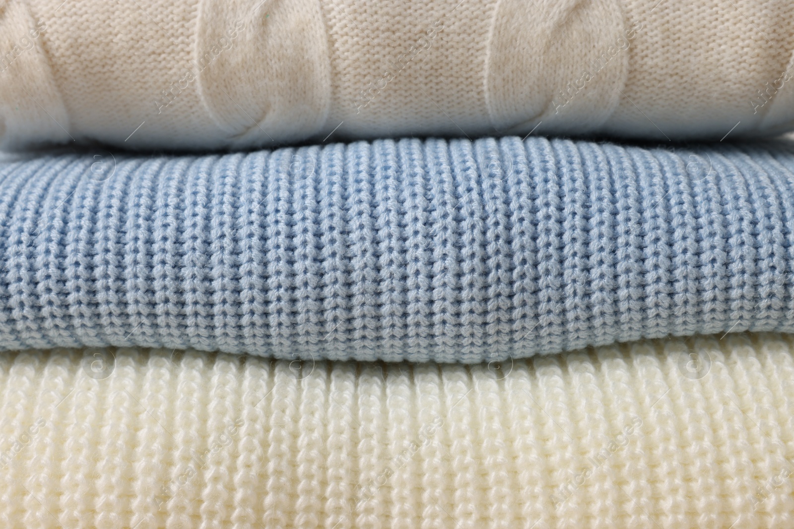 Photo of Stack of casual warm sweaters as background, closeup view