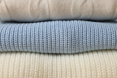 Stack of casual warm sweaters as background, closeup view