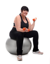 Photo of Happy overweight mature woman with dumbbells sitting on fitness ball against white background