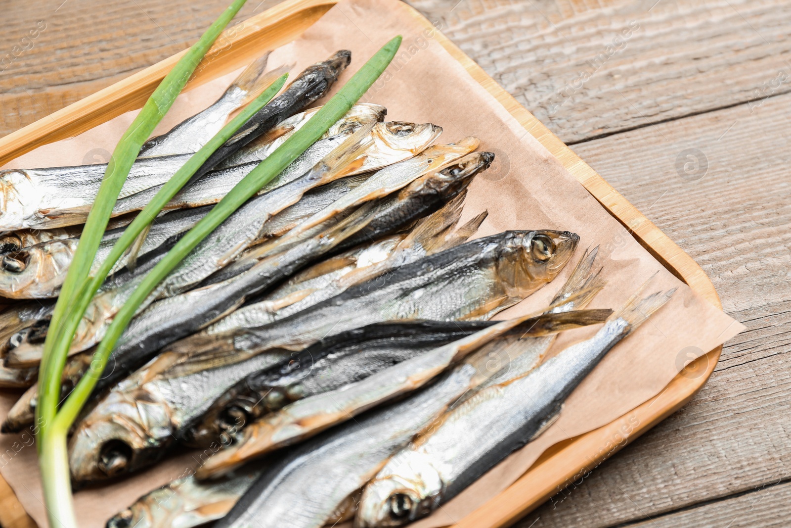 Photo of Tasty dried fish with fresh onion on wooden table, closeup