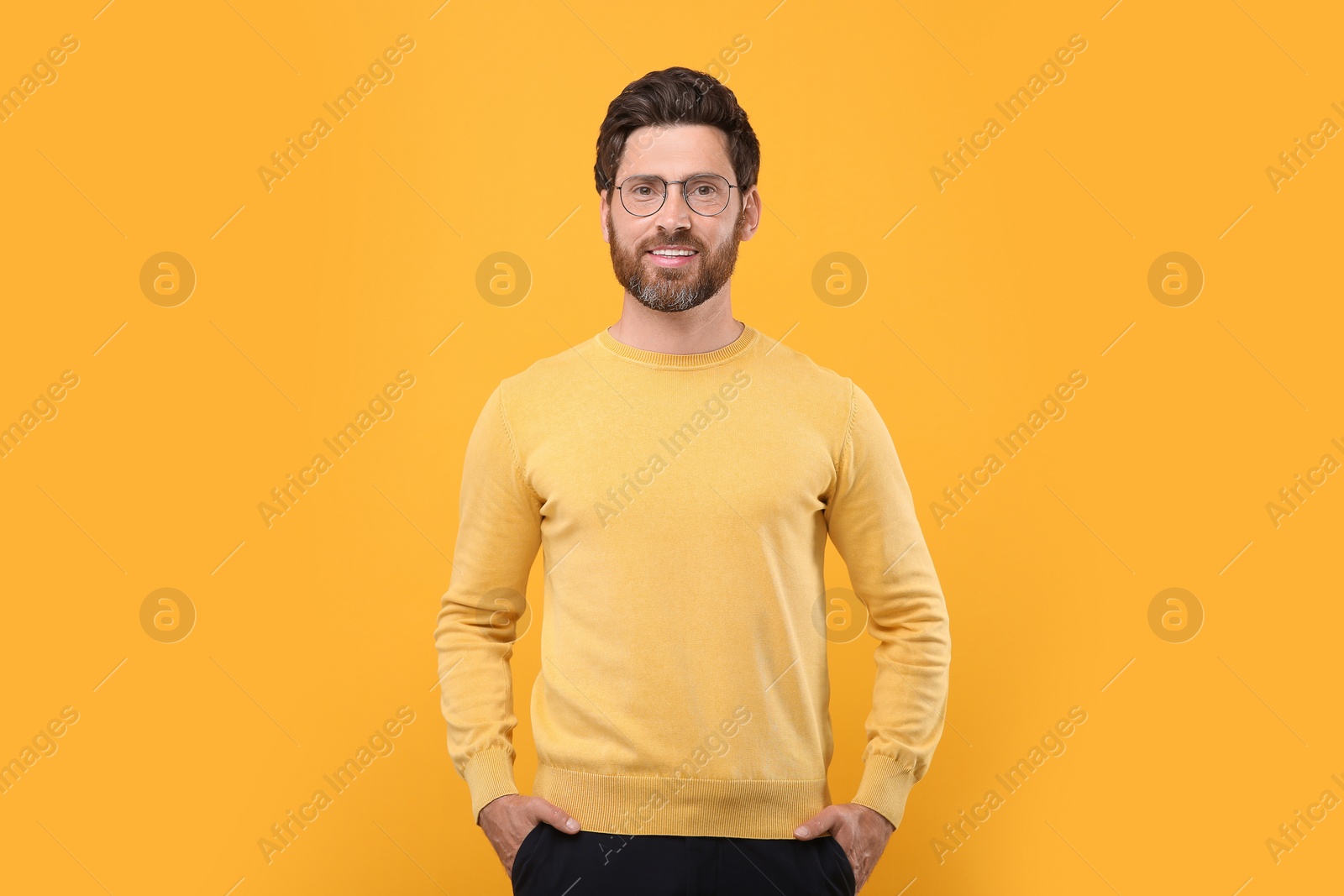 Photo of Portrait of handsome man in glasses on orange background
