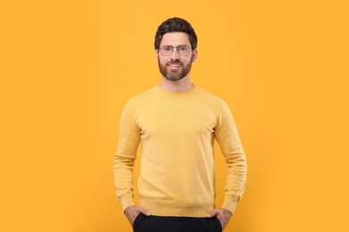 Portrait of handsome man in glasses on orange background