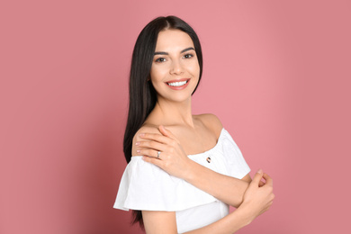 Photo of Happy young woman wearing beautiful engagement ring on pink background