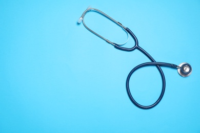 Photo of Modern stethoscope on light blue background, top view. Space for text