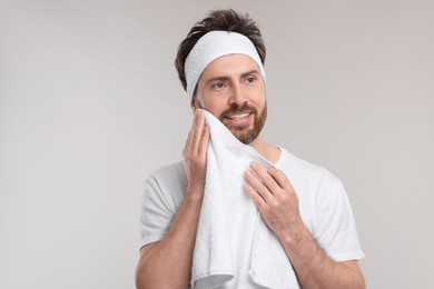Photo of Washing face. Man with headband and towel on light grey background