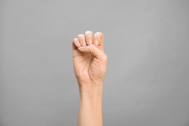 Photo of Woman showing E letter on grey background, closeup. Sign language