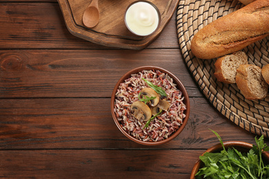 Photo of Delicious brown rice served on wooden table, flat lay