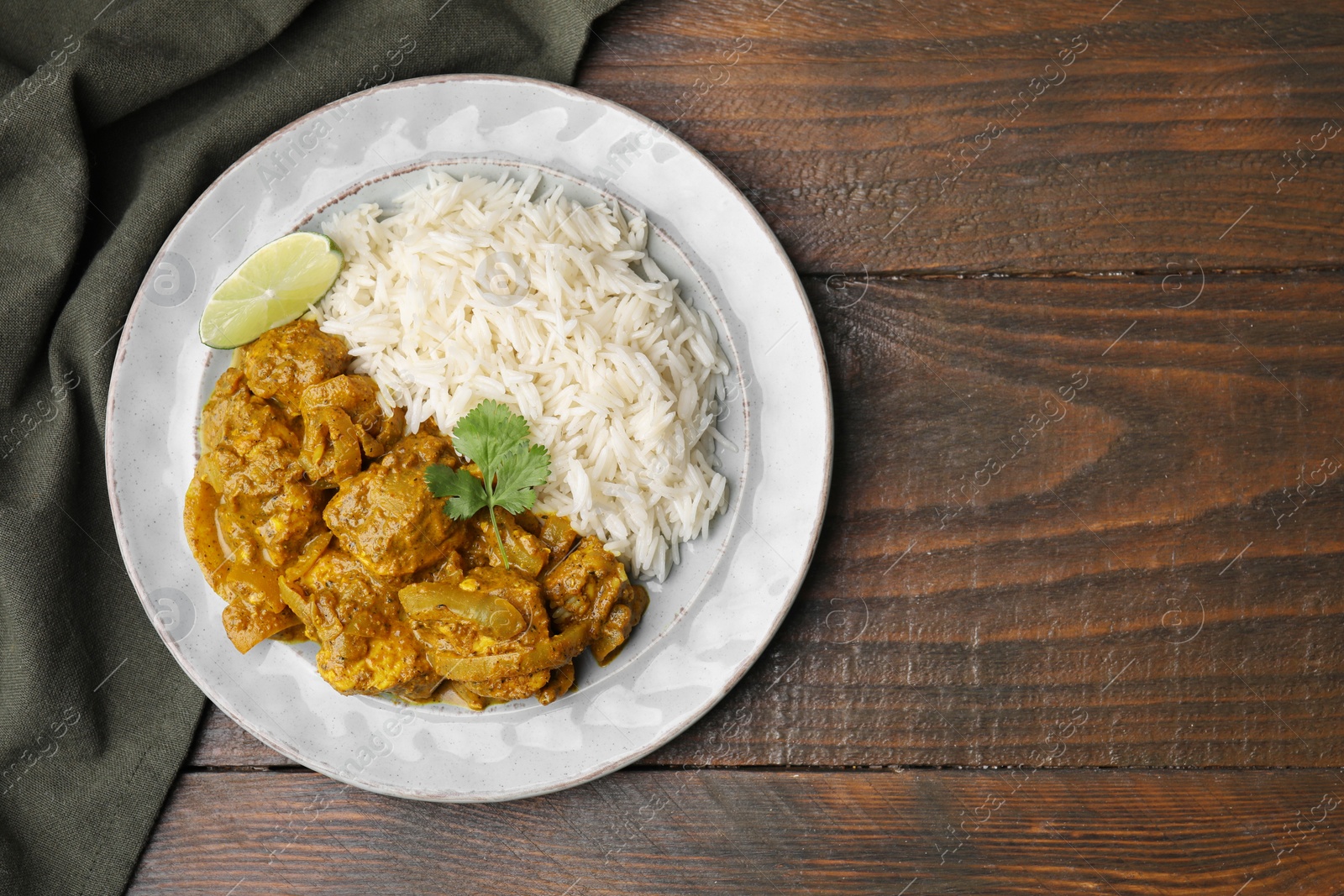 Photo of Delicious chicken curry with rice on wooden table, top view. Space for text