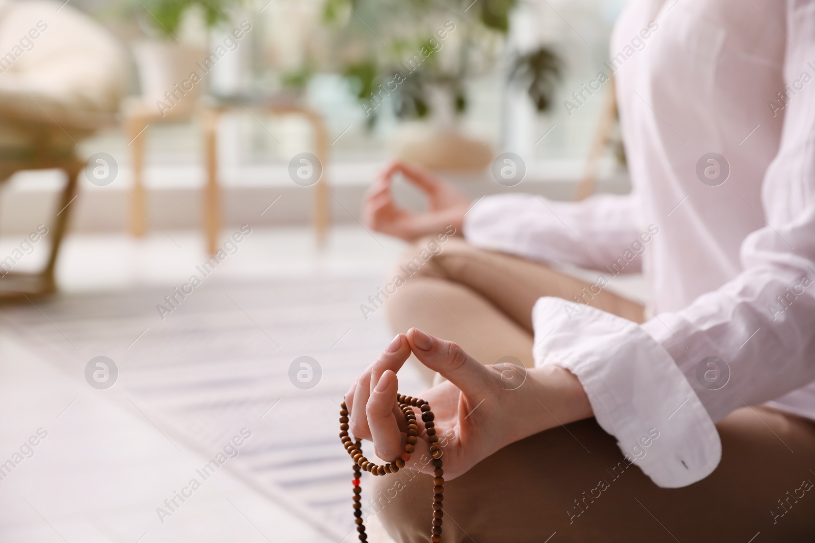 Photo of Woman with beads meditating at home, closeup. Space for text