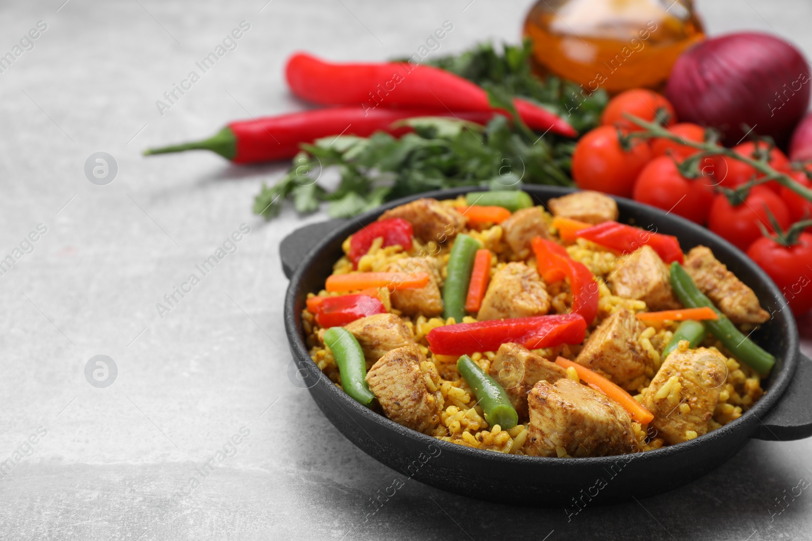 Photo of Serving pan of delicious rice with chicken and vegetables on light grey table, closeup. Space for text