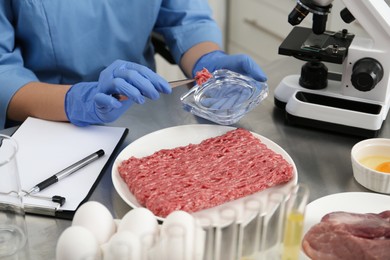 Photo of Scientist checking meat at table in laboratory, closeup. Quality control