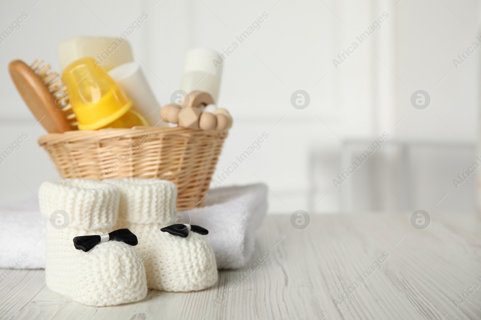 Photo of Baby booties and accessories on white wooden table indoors. Space for text