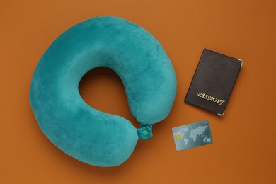 Photo of Turquoise pillow, passport and credit card on orange background, flat lay