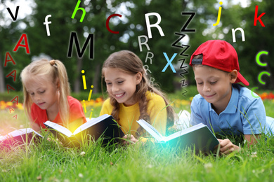 Image of Group of little children reading books on green grass in park