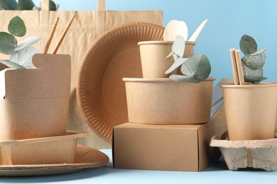 Photo of Eco friendly food packaging. Paper containers, tableware, bag and eucalyptus branches on white table