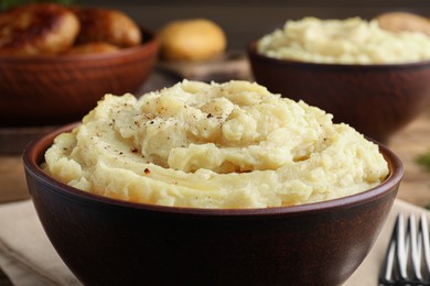 Photo of Bowl of tasty mashed potatoes with black pepper on table, closeup